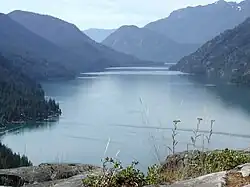 Narrow lake extending toward the background between forested mountains