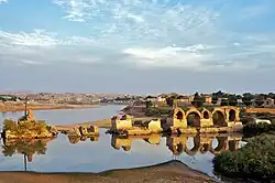 The remains of a bridge and dam, in a calm lake.