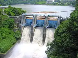 A reservoir behind a dam, with water flowing over the top of the dam