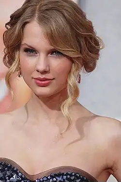 Taylor Swift wearing a dark strapless dress with her hair pinned up