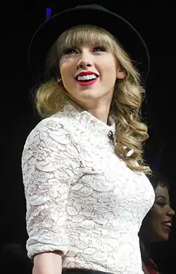 Swift in a white laced oxford shirt and black fedora hat