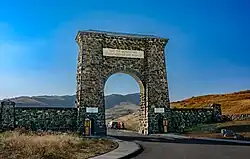 A large arch made of irregular-shaped natural stone over a road