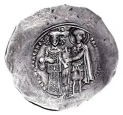 Round silver coin with two standing figures, the left one dressed in regalia and the right one as a warrior saint, handing a castle to the former