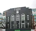 The Time Building on Station Road with a Miller-branded clock - formerly home of Time nightclub in 2000; today part converted into residential use[104]