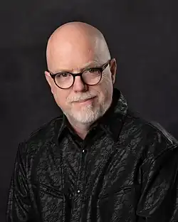 Head and torso of bald man with glasses