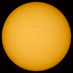 Transit of Mercury. Mercury is visible as a black dot below and to the left of center. The dark area above the center of the solar disk is a sunspot.