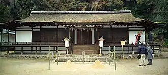 Frontal view of a rather low and wide building with wooden beams and white painted walls.