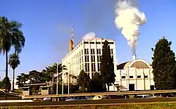 Photo of shorter building with smoke coming out of smokestack next to five-story office building