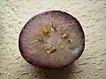A cut blueberry showing how, having been frozen and then thawed, the anthocyanins in the pericarp can run into the flesh