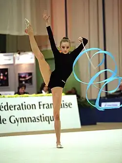 Stadnik stands in a split and twirls the ribbon