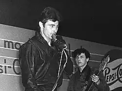 A black and white photo of singer Vince Taylor in front of a microphone