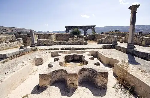View across a ruined bath complex showing the basins and water features