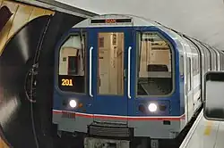 An underground train on a station platform. Unlike modern tube trains it has a clear NSE blue, red, and grey livery. It is desplaying its destination as BANK and its number as 201