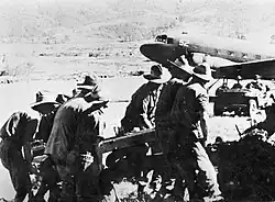 Soldiers in slouch hats manhandle an artillery piece from a plane