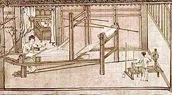 A woman weaves the silk thread on a large, room-length loom, while a child spins more thread in the corner.
