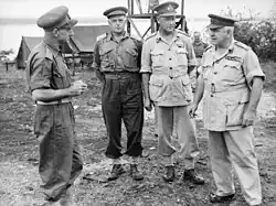 Four men in uniforms without ties, but wearing peaked caps.