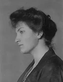 Head and shoulders photo portrait of an attractive dark-haired young woman looking left with a thoughtful expression