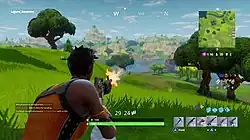 The player, on a hill, shoots into the distance toward a large lake.