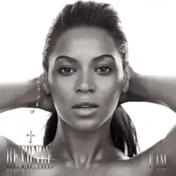 The cover of the album "I Am... Sasha Fierce" features a black and white profile of Beyoncé. She is looking directly at the camera with her hands behind her head. Her hair is styled in a ponytail, and she wears a bracelet on her right wrist. At the lower-left corner, her first name is written in capital silver letters, while "I Am..." is written in a similar style at the right corner.