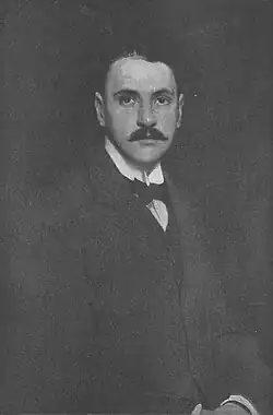 young man with neat dark hair and moustache, wearing a wing-collar and bow-tie in a dark suit
